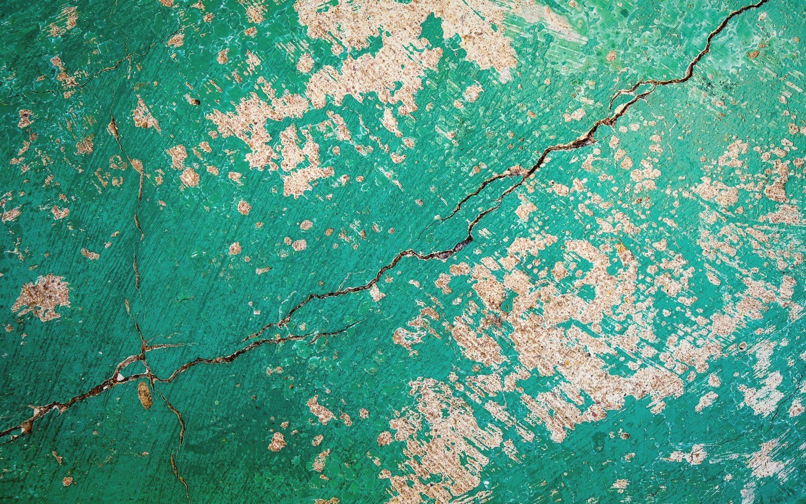 Cracked green paint peeling away to reveal rusty orange patches underneath