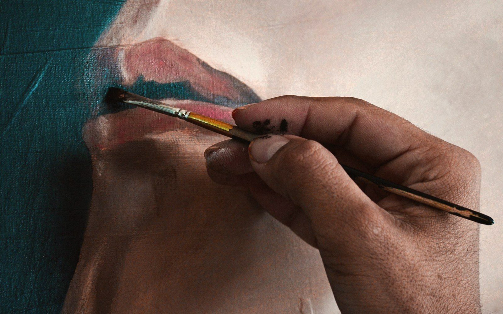 A close-up of a hand using a small brush to retouch an oil painting