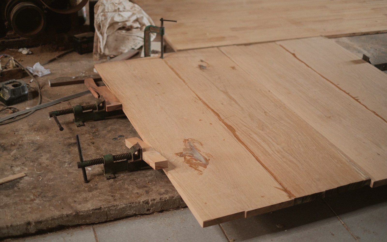 Wood boards being glued and clamped together on a workshop floor